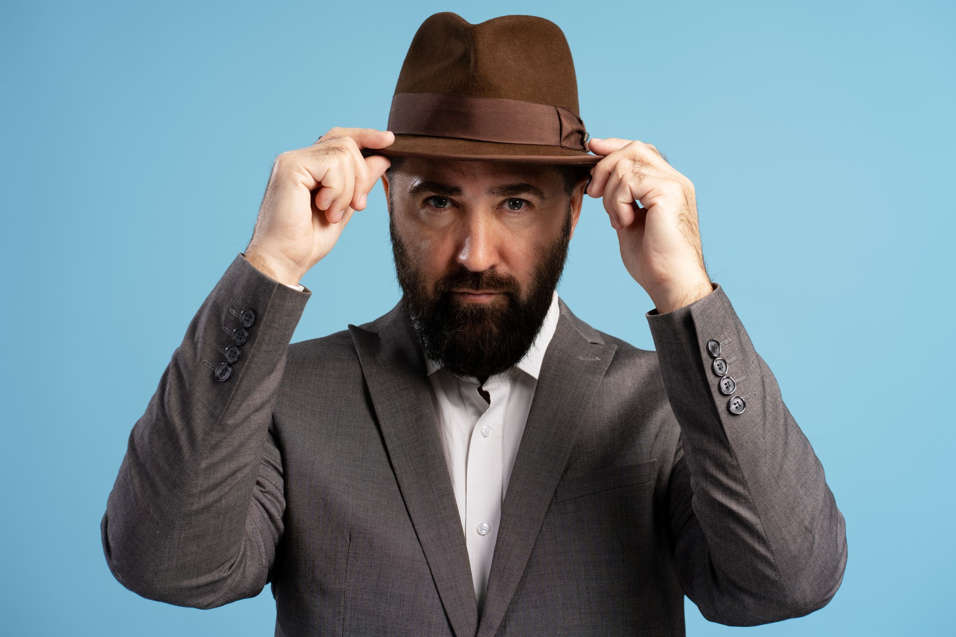 Elegant businessman adjusting his brown fedora hat