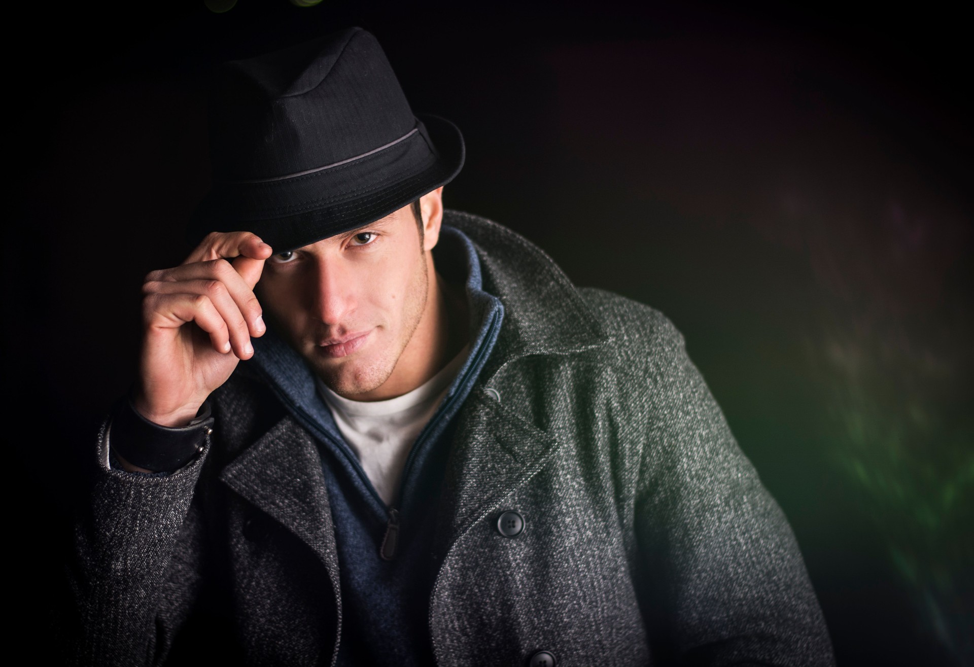 Attractive young man at night, wearing winter coat and fedora